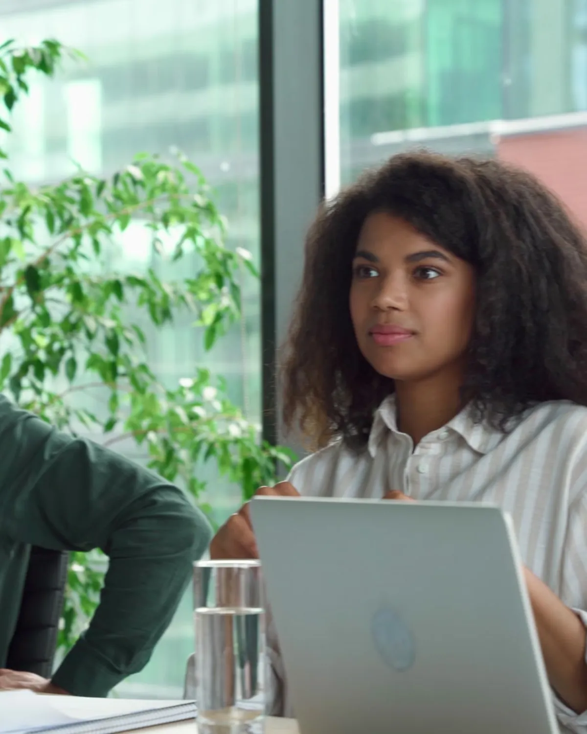 A team listens in a meeting room, laptops open