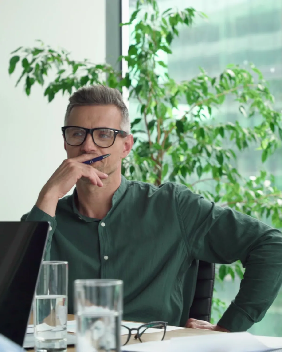 Colleagues in a meeting, one listening with his hand to his chin