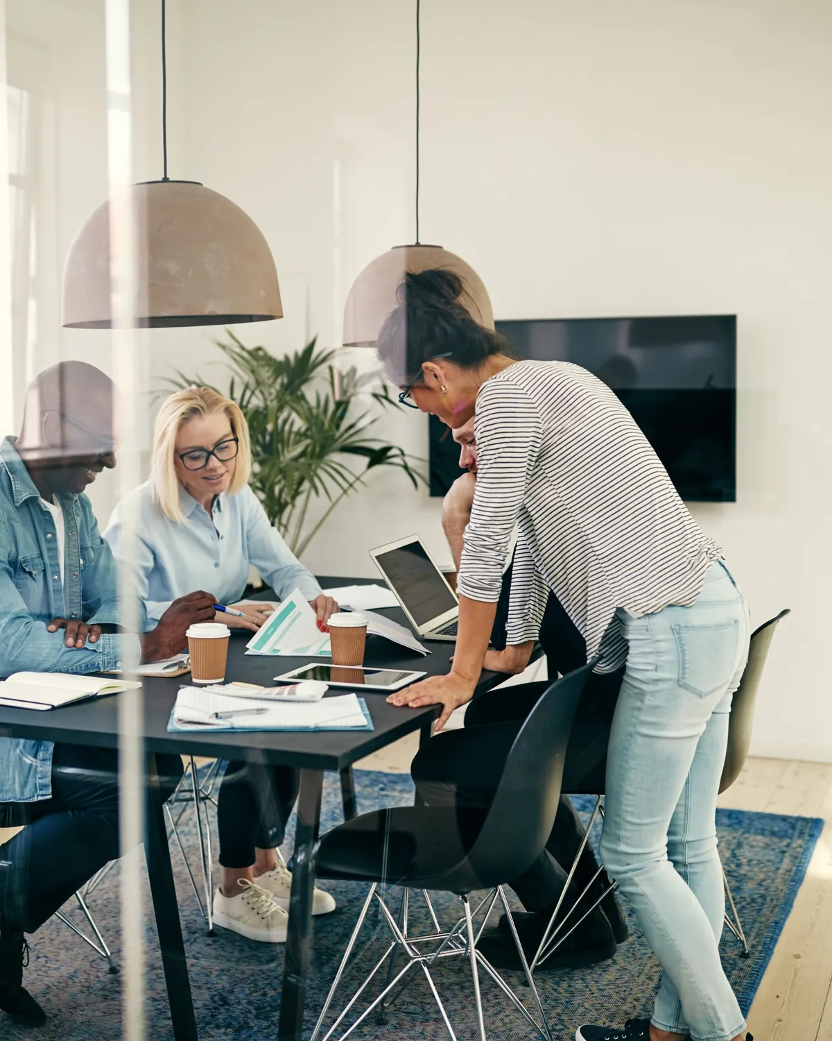 A small team working over papers and a laptop in a bright meeting room